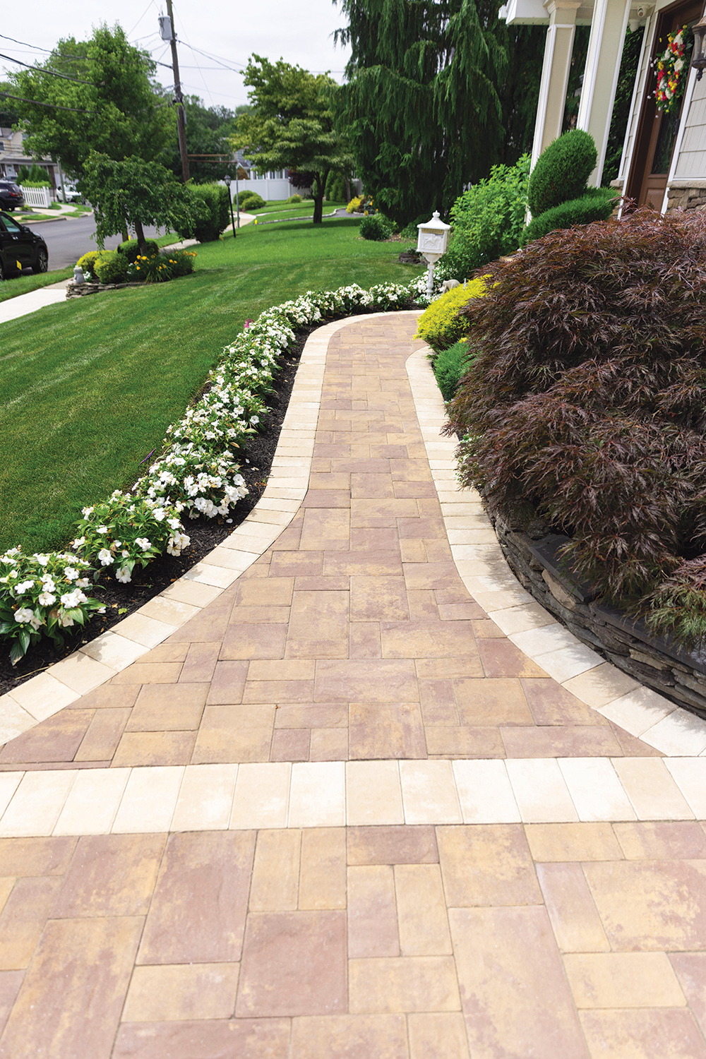 Curved paver walkway lined with white impatiens